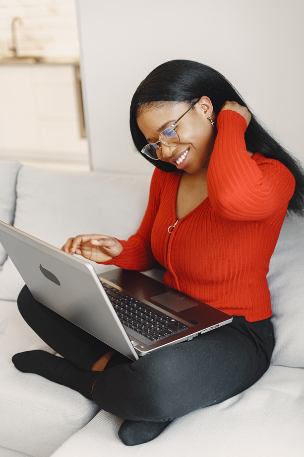 Woman with a laptop. International girl on a bed. Lady working.